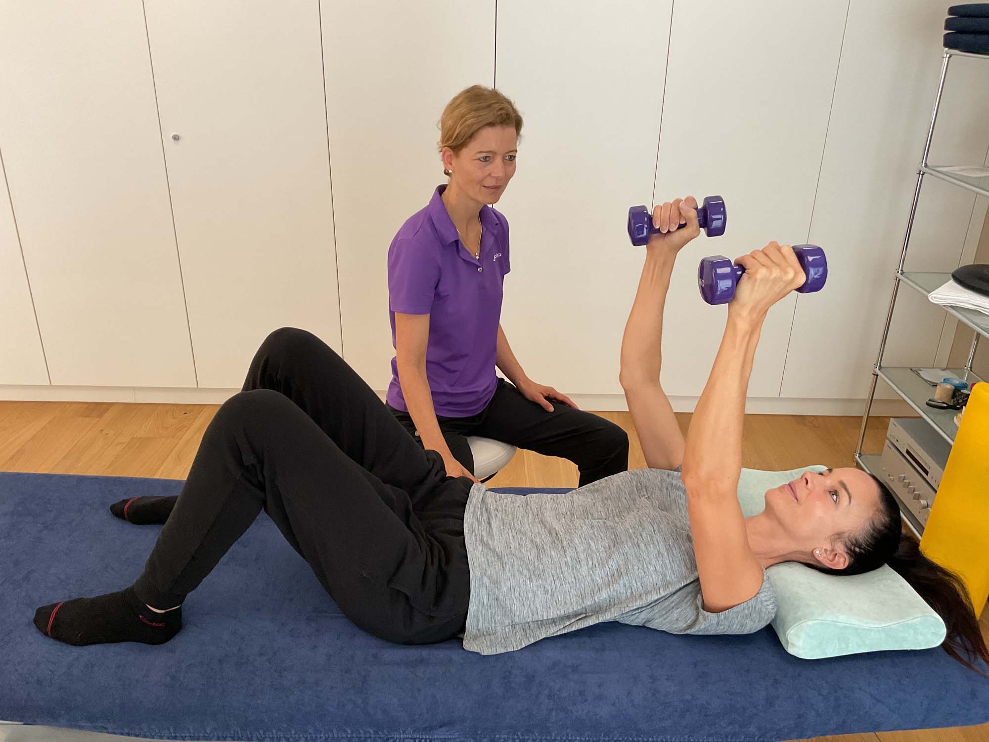 Eine Frau macht unter Anleitung einer Physiotherapeutin eine Übung zur körperlichen Rehabilitation.