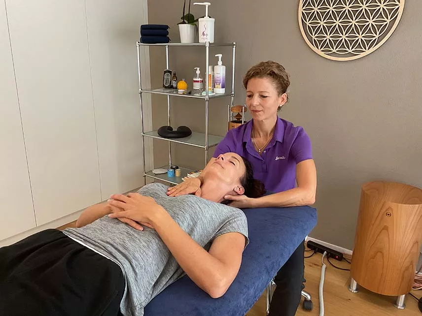 Eine Frau erhält eine Massage in einem Raum. Physiotherapie mit Craniosacral Therapie.