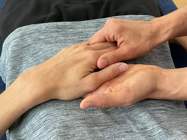 Eine Physiotherapeutin hält die Hand einer anderen Person. Jin Shin Jyutsu - eine heilende Berührung.