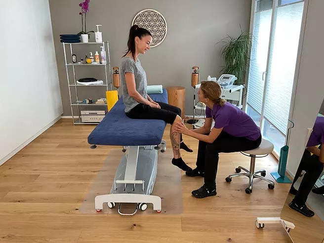 Physiotherapie, professionelle Behandlung von einer Physiotherapeutin am Bein einer Frau.